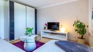 A modern living room with a sofa, a glass coffee table, a flat-screen TV, a lamp, and a potted plant. - Special Apartment in Walchen With Private Terrace (Piesendorf)