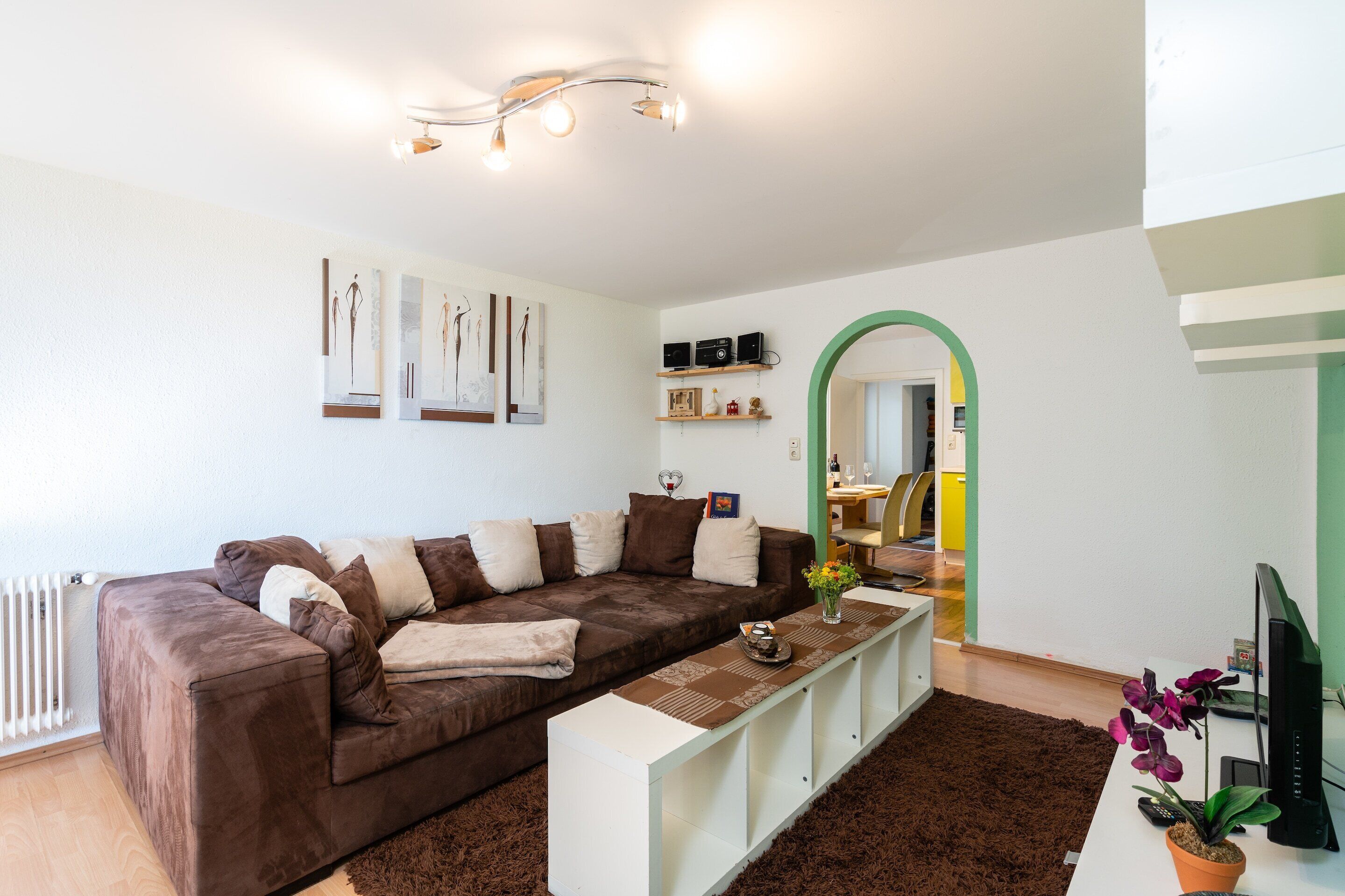 Una sala de estar moderna con un sofá marrón, una consola blanca y una planta en maceta.