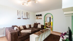 A modern living room with a brown sofa, white console table, and a potted plant. - Special Apartment in Walchen With Private Terrace (Piesendorf)