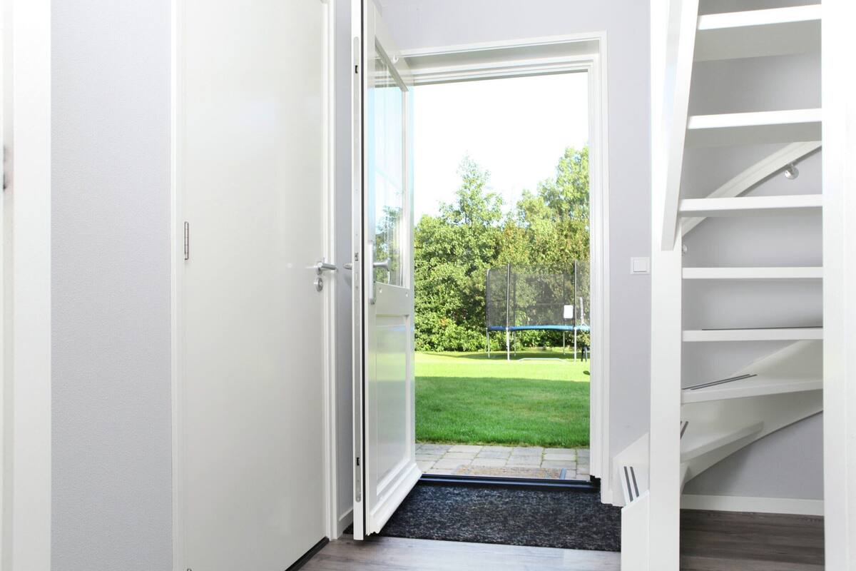 A modern interior with a glass door leading to a backyard with a trampoline.