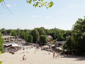 A beach with a large open area, a church spire in the background, and surrounding greenery.
