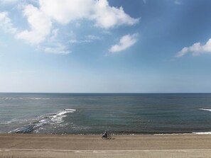 Eine Küstenstraße mit einem Radfahrer, blauem Himmel und ruhiger See.