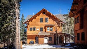 A large wooden cabin with a central entrance, multiple windows, and a covered porch area.