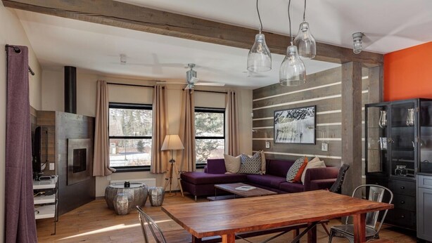 A modern living room with a wooden dining table, purple sofa, and a black cabinet.