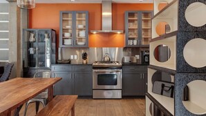 A modern kitchen with grey cabinets, a stainless steel stove, and a wooden dining table.