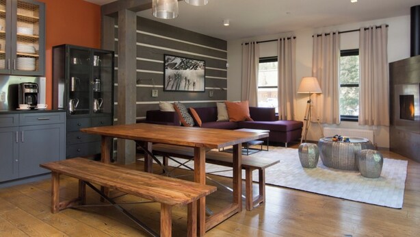 A modern living room with a wooden dining table, a sofa, and a fireplace. - Bavarian Chalet 1 - Bavarian-inspired chalet with stylish decor and easy ski acc (Taos Ski Valley)