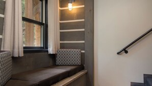 A cozy seating area with a cushioned bench, a patterned pillow, and a window with curtains. - Bavarian Chalet 1 - Bavarian-inspired chalet with stylish decor and easy ski acc (Taos Ski Valley)