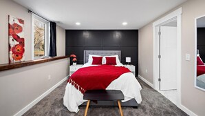 Une chambre à coucher avec un lit, des tables de chevet, une fenêtre avec des rideaux et une porte.