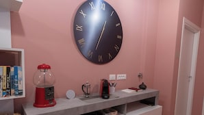 A modern living room with a pink wall, a large round clock, a red coffee machine, and a bookshelf. - Cà Cianfer (Bergamo)