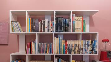 Ein Bücherregal mit mehreren Reihen Bücher vor einer rosafarbenen Wand.