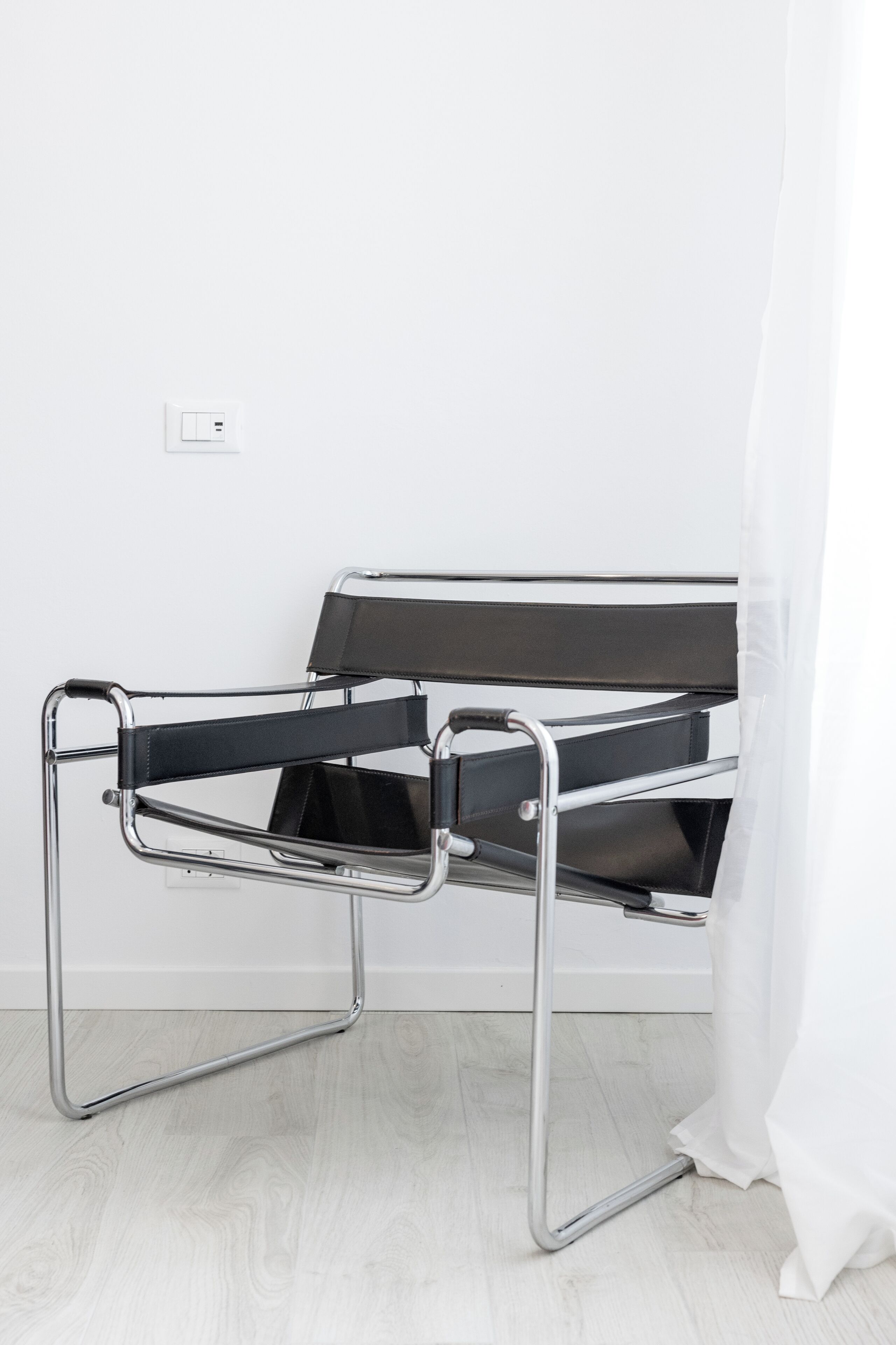 A modern room with a minimalist design, featuring a metal-framed bed with a black mattress and metal frame.