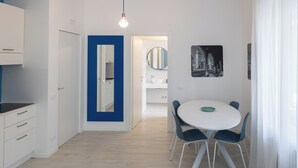 A modern kitchen with white cabinets, a blue accent wall, and a dining area with a round table and chairs. - Cà Cianfer (Bergamo)
