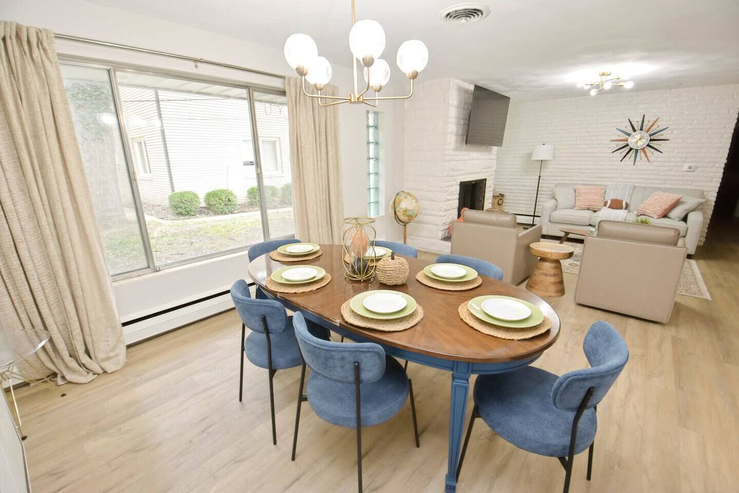 A dining area with a round table, blue chairs, and a chandelier.