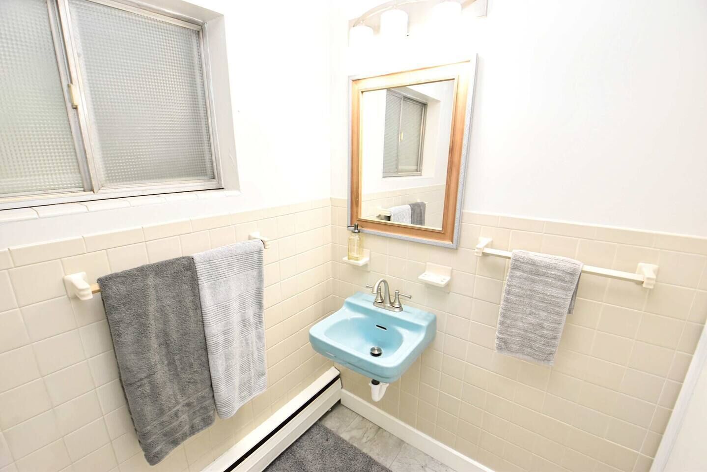 A bathroom with a window, a sink, and two towels on towel racks.