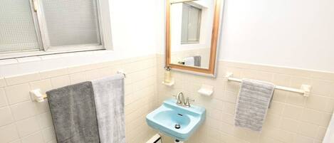 A bathroom with a window, a sink, and two towels on towel racks.