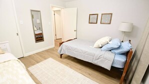 A bedroom with a bed, a bedside table, a lamp, a mirror, and a door leading to another room. - Mid Century Modern, 10 min walk to ND! (1831) (South Bend)