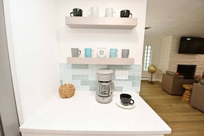 Une cuisine équipée d’une machine à café, d’une tasse et d’un objet décoratif posé sur le comptoir.
