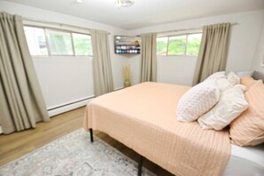 A bedroom with a bed, curtains, a flat-screen TV, and a window. - Mid Century Modern, 10 min walk to ND! (1831) (South Bend)