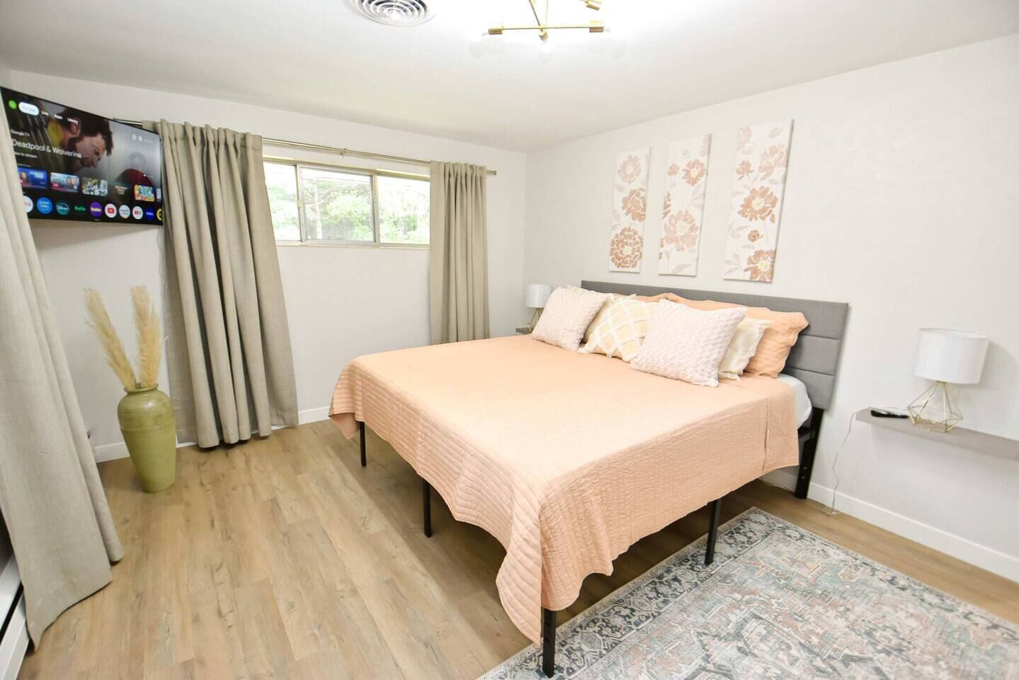 A bedroom with a bed, curtains, a television, and a window.