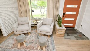 A room with two armchairs, a small table, a patterned rug, a potted plant, and a door with frosted glass panels. - Mid Century Modern, 10 min walk to ND! (1831) (South Bend)