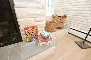 A fireplace area with a Giant UNO card game, a Scrabble set, and a box of Charades for Kids.