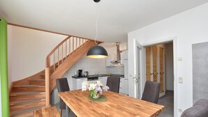 A modern kitchen with a wooden staircase, a dining table with chairs, and a pendant light. - Idyllic Holiday Home in Damshagen With Terrace (Damshagen)