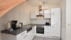 A modern kitchen with white cabinets, a built-in oven, a coffee maker, and a kettle on the countertop. - Idyllic Holiday Home in Damshagen With Terrace (Damshagen)