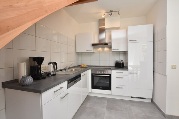 A modern kitchen with white cabinets, a built-in oven, a coffee maker, and a kettle on the countertop. - Idyllic Holiday Home in Damshagen With Terrace (Damshagen)