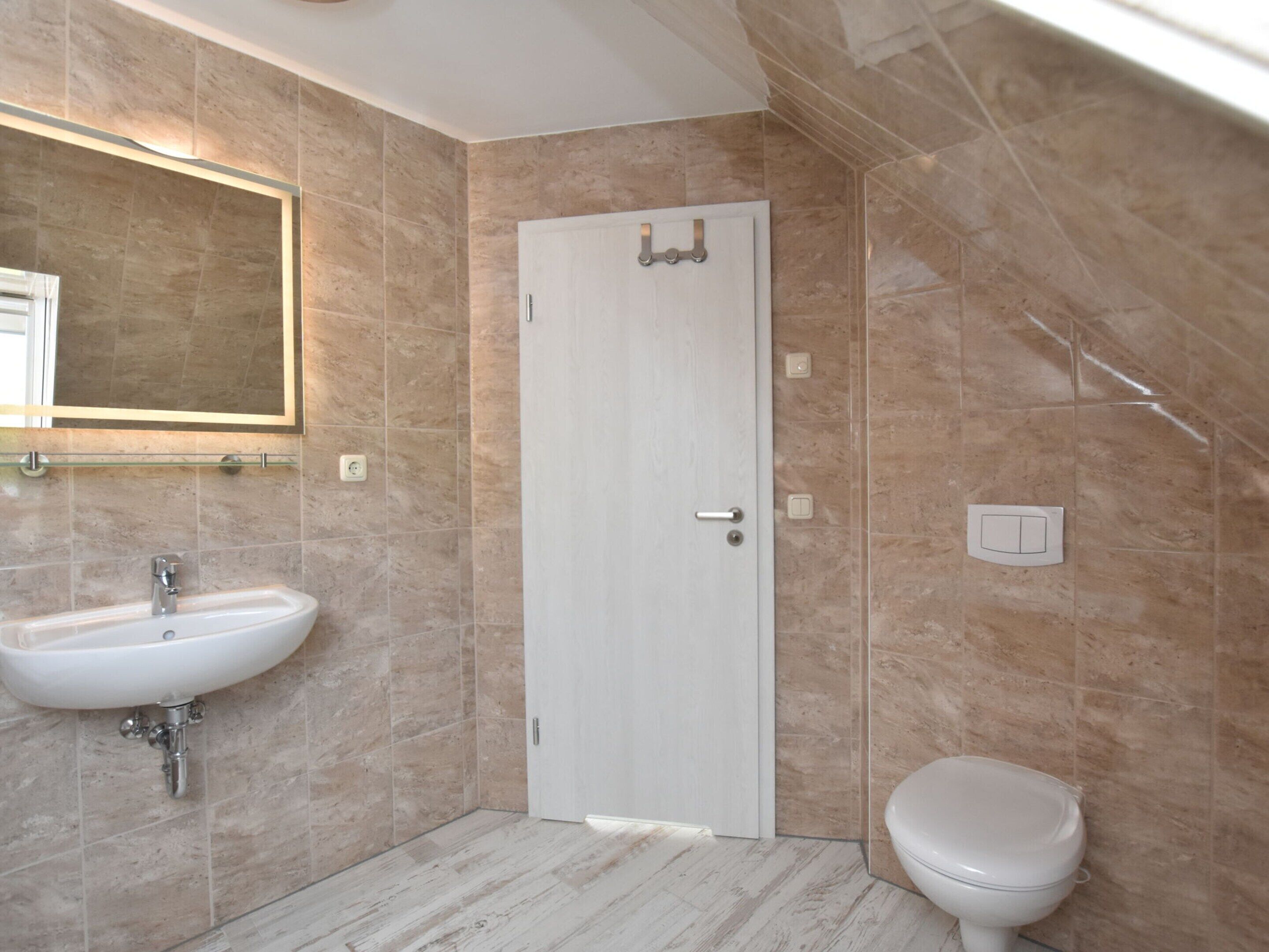 A bathroom with a white sink, a toilet, and a door with a towel rack.