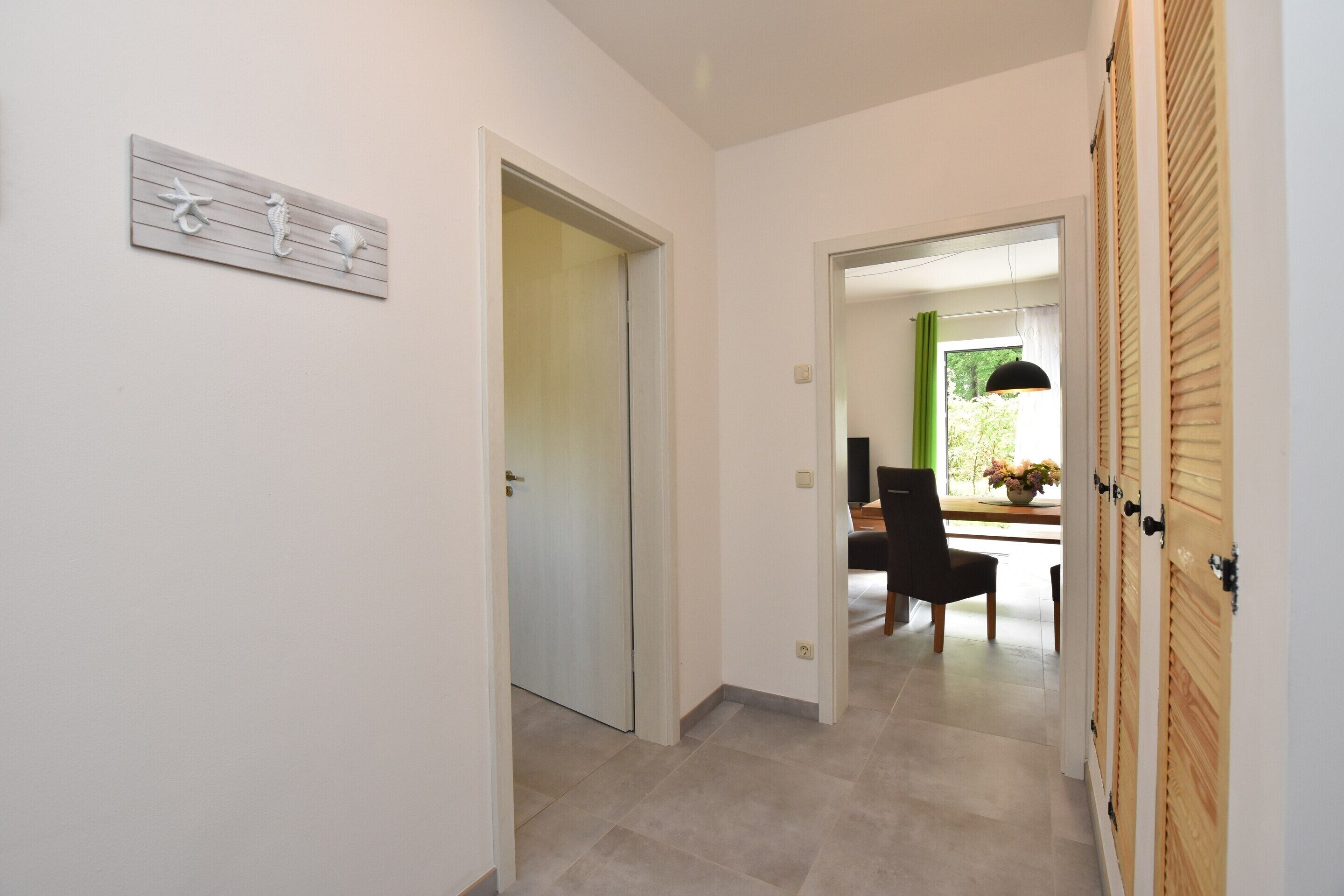 A hallway with a wooden door, a wall-mounted decoration, and a view into a dining area with a table and chairs.