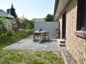 Un patio con tavolo e sedie, un muro in mattoni e un piccolo giardino.