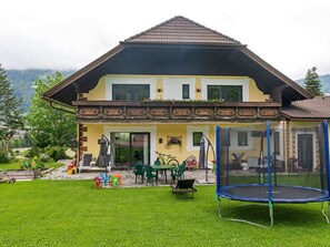 A two-story house with a balcony, a trampoline, and a garden with outdoor furniture. - Spacious Apartment in Katschberg (Sankt Michael im Lungau)