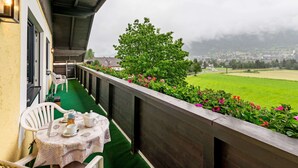 A balcony with a table set for tea, overlooking a green field and a town in the distance. - Spacious Apartment in Katschberg (Sankt Michael im Lungau)