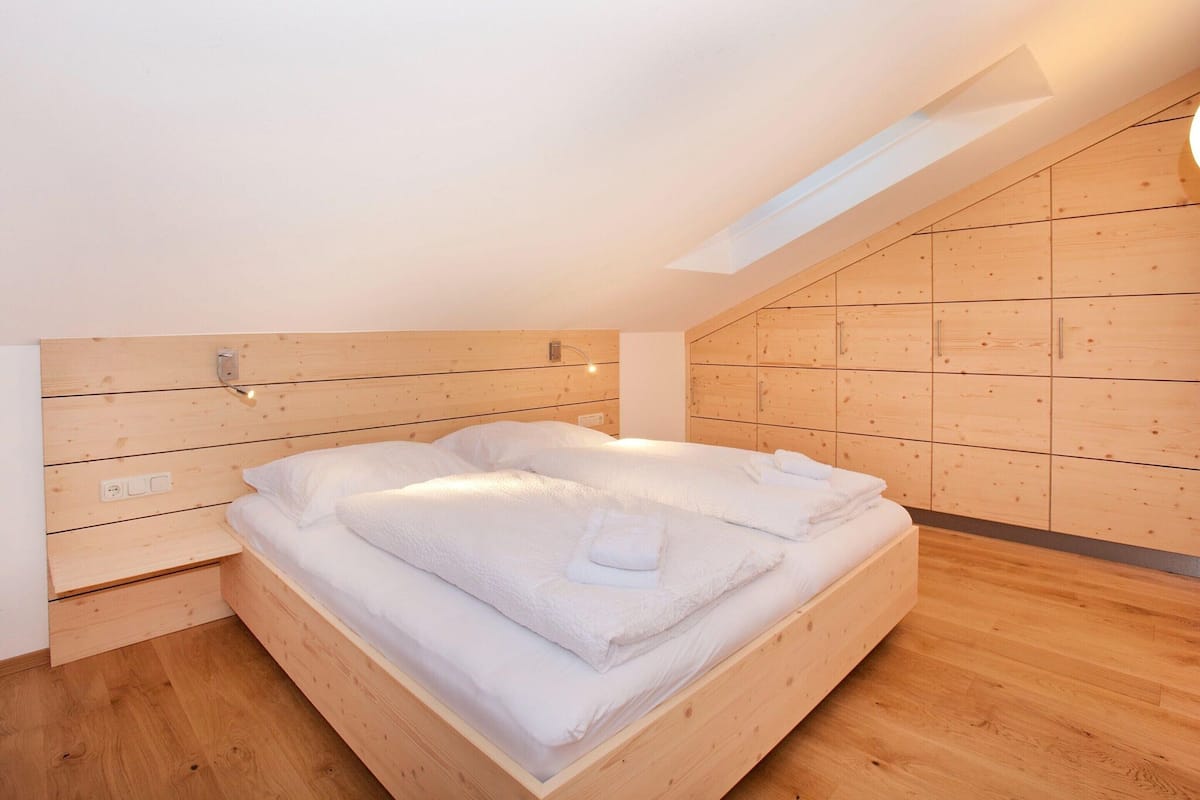 A bedroom with a wooden bed, a sloped ceiling, and a built-in wardrobe.