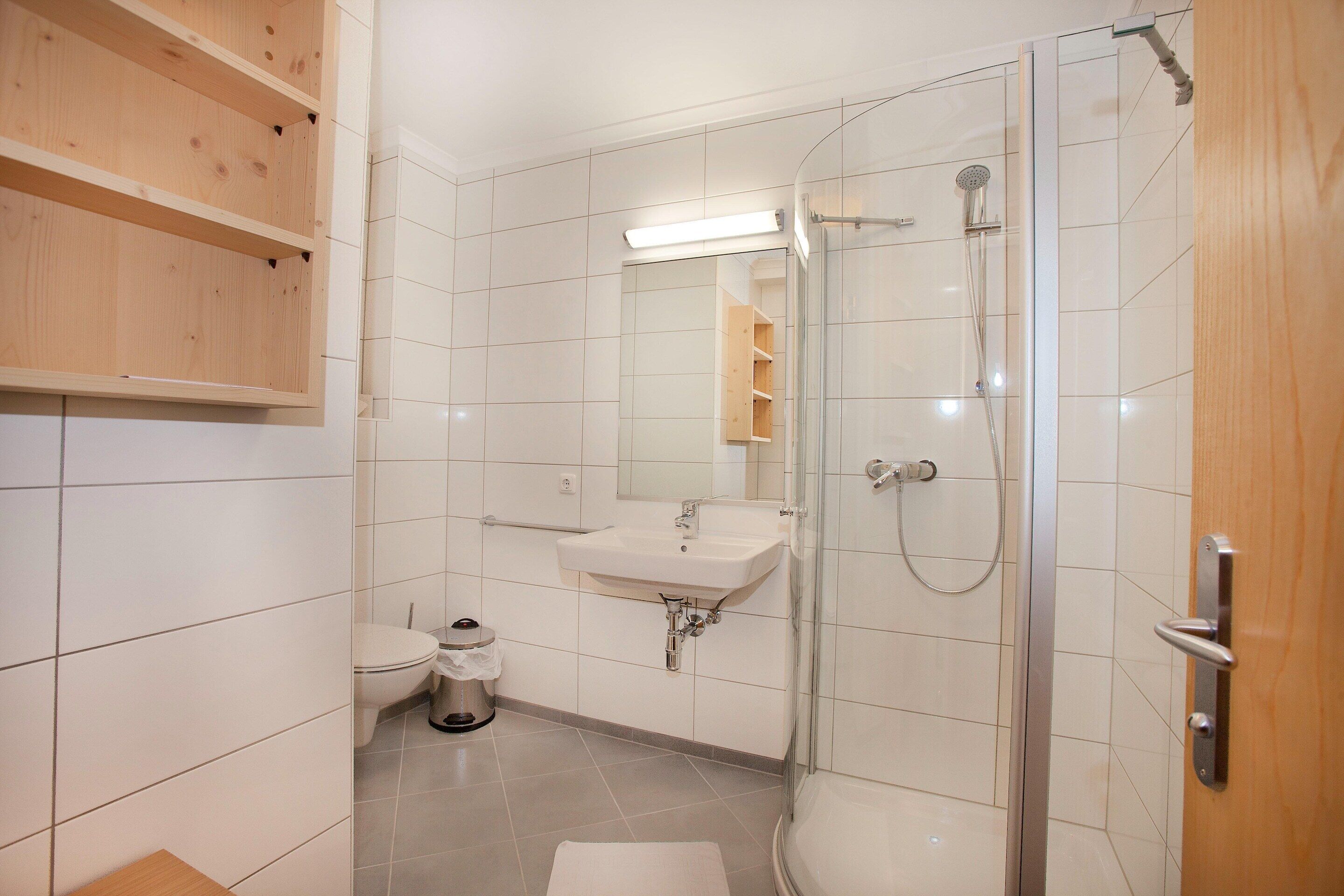 A modern bathroom with a glass-enclosed shower, a sink, and a toilet.