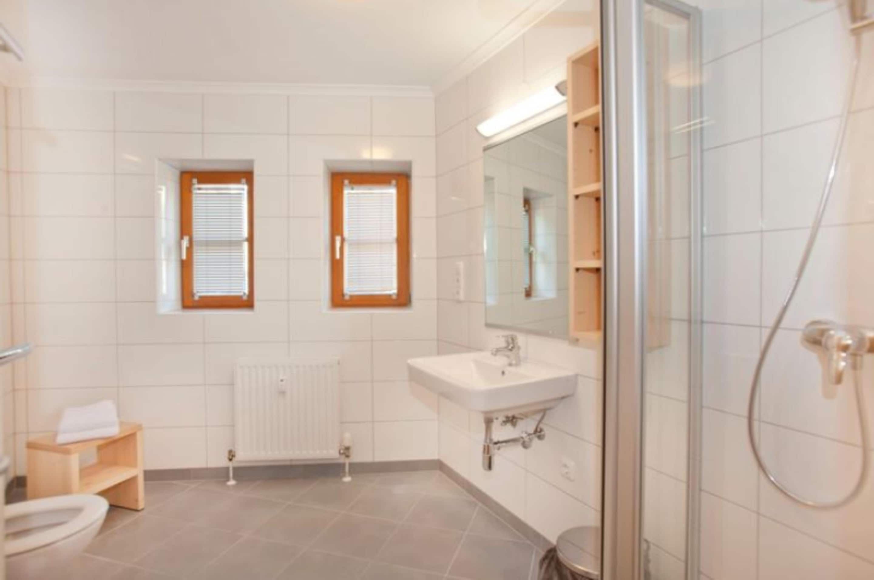 A modern bathroom with a shower, toilet, and sink.