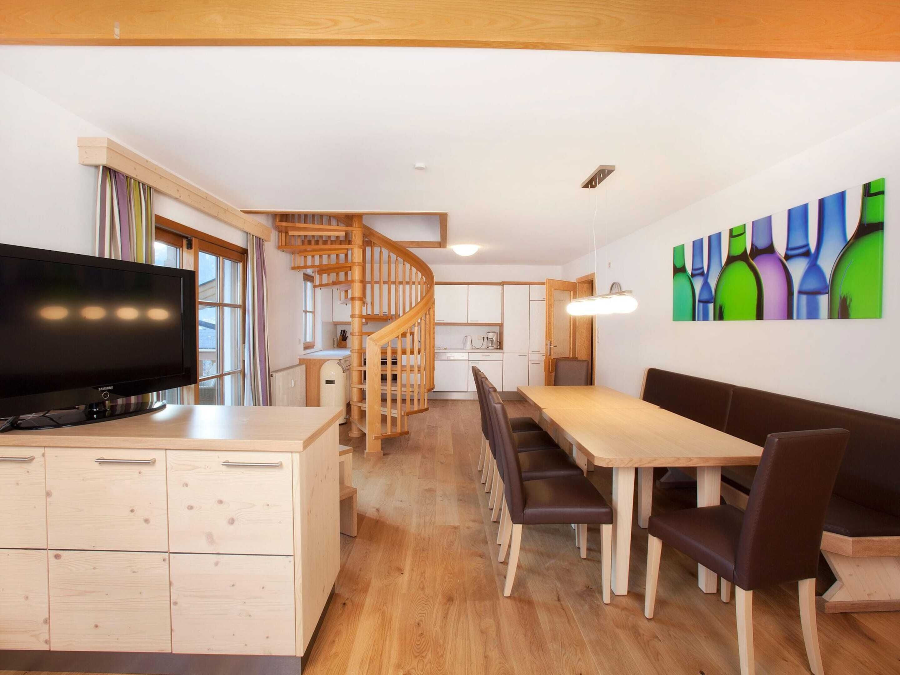A modern kitchen with wooden cabinets, a built-in stove, and a dining area with a wooden table and chairs.