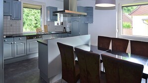 Une cuisine moderne avec des meubles de couleur grise, un îlot central et un coin repas avec des chaises.