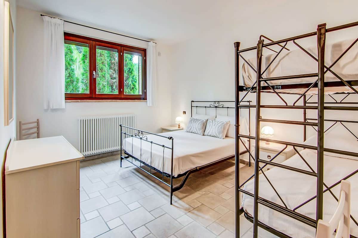 A bedroom with a single bed, a desk, and a window with curtains.