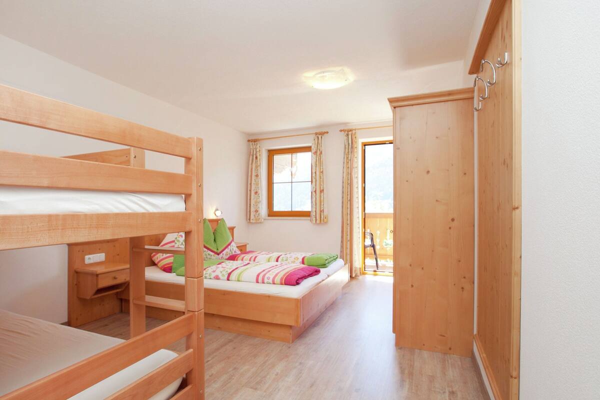 A room with a bunk bed, a desk, a chair, and a wardrobe.