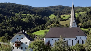 En kyrka med ett högt torn och en vit byggnad med en balkong i förgrunden.