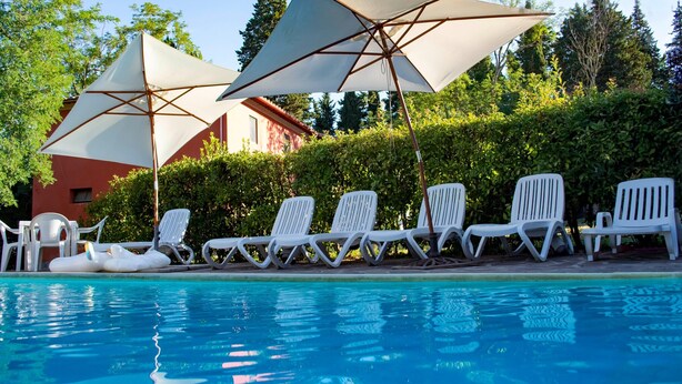 Un espace piscine équipé de chaises longues et de parasols.
