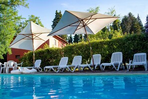 Un espace piscine équipé de chaises longues et de parasols.