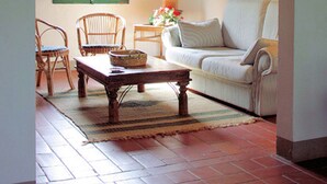 Un salon chaleureux avec un plafond en bois rustique, un canapé blanc, une table basse en bois et une fenêtre avec des volets.