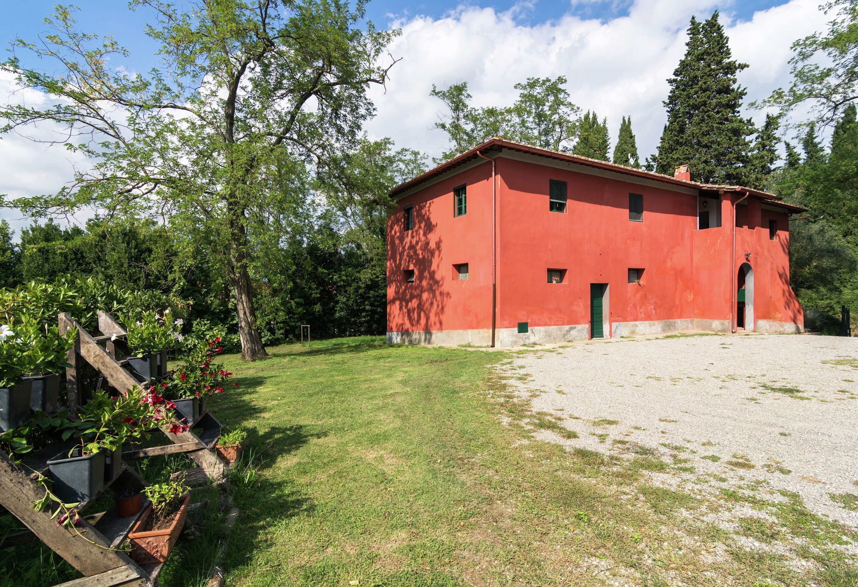 A red building with a gravel courtyard and a garden with wooden planters.