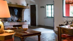 Une pièce chaleureuse avec une cheminée en briques, une table en bois et une fenêtre donnant sur un paysage verdoyant.