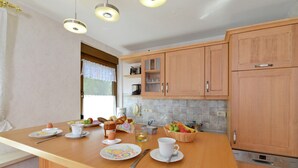 A modern kitchen with wooden cabinets, a central island with breakfast items, and a Bosch dishwasher.