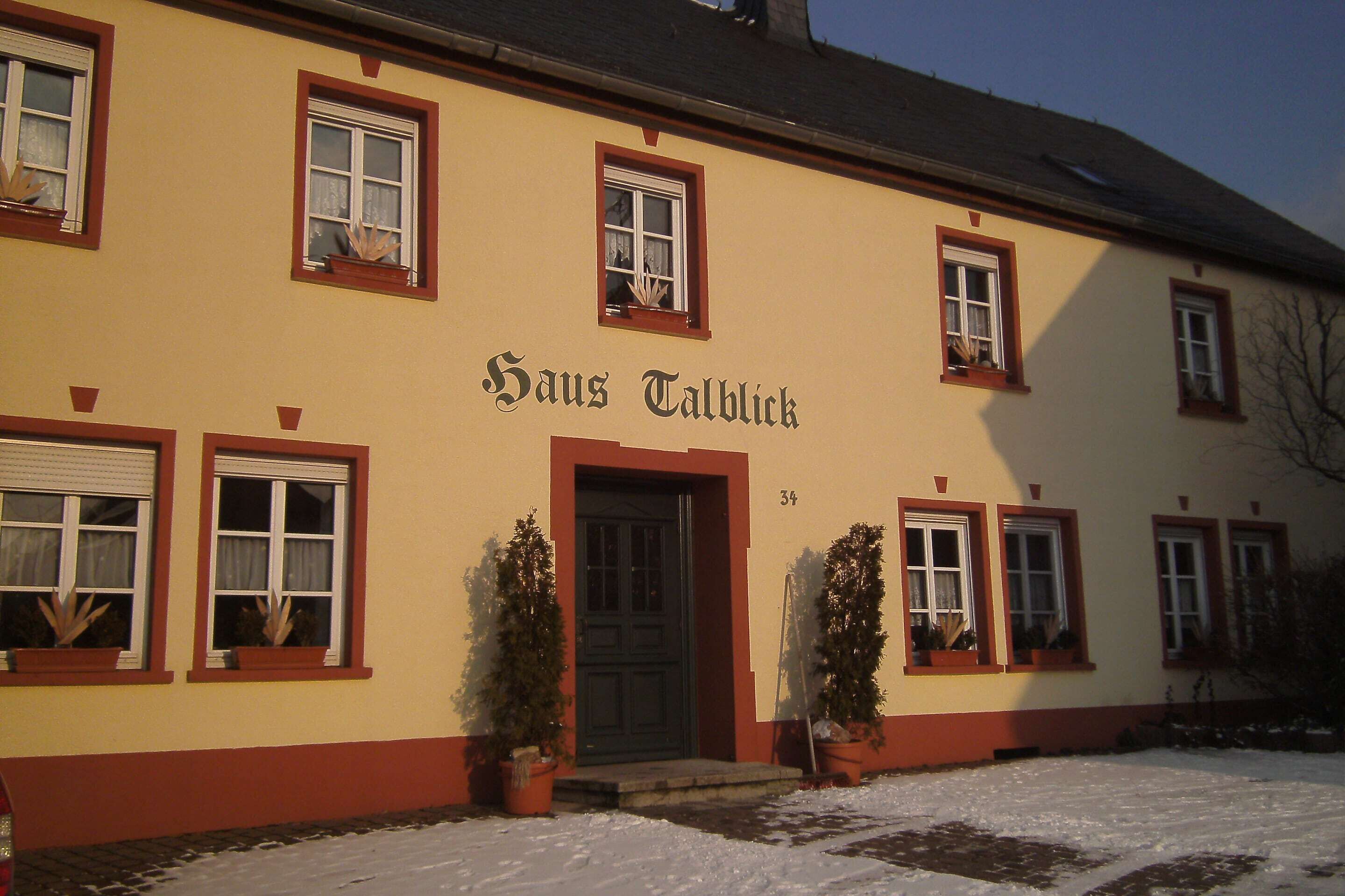 Un edificio con el nombre "Hans Talblick" en la fachada, con varias ventanas y una puerta, rodeado de nieve.