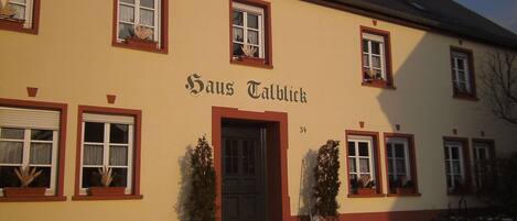 Un edificio con el nombre "Hans Talblick" en la fachada, con varias ventanas y una puerta, rodeado de nieve.