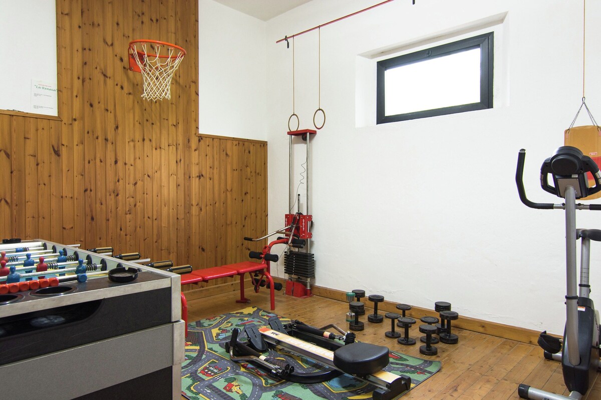 A gym with a foosball table, weightlifting equipment, a bench, and a window.